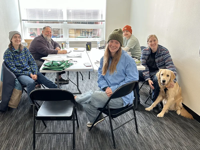 Canvassing crew and their dog around the table at the Eugene field office, sorting petition sheets